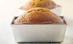 two muffins sitting in tins on top of a white countertop next to each other