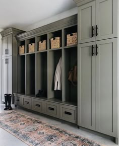 an organized mud room with gray cabinets and baskets on the wall, carpeted floor