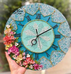 a hand holding a clock decorated with flowers