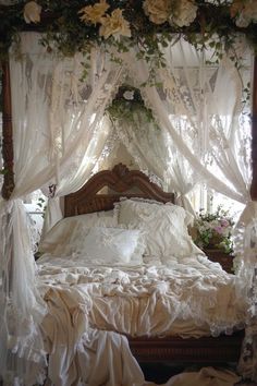 a bed with white sheets and flowers on the headboard is covered by sheer curtains