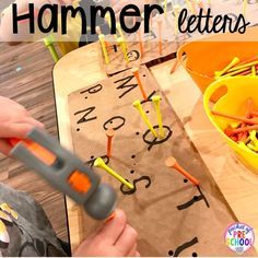 a child is playing with hammer letters on a piece of paper and plastic construction equipment