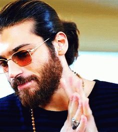 a man with a beard wearing sunglasses and holding his hands together