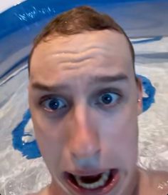 a man in the water with his mouth open and eyes wide open, making a weird face