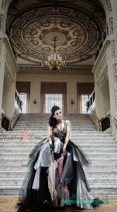 a woman sitting on top of a stair case in front of a chandelier