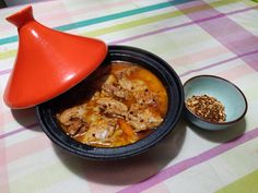 a bowl of food on a table with a red lid