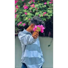 a young boy holding pink flowers in his hand