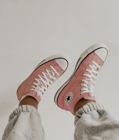 a person wearing pink converse sneakers with white laces