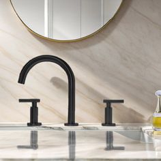 a bathroom sink with two faucets and a round mirror