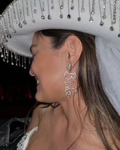 a woman wearing a white hat and earrings