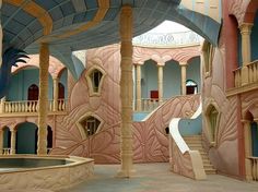 the inside of a building with pink walls and arches, stairs, and a fountain