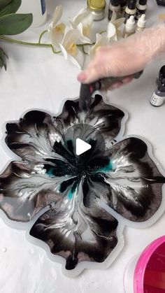 a person is painting a flower with black and white paint on it's petals