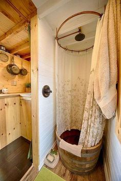 a bathroom with a wooden tub and shower curtain in it's corner, next to a green rug