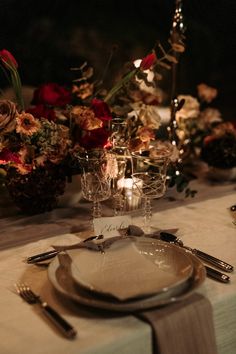 the table is set with silverware, flowers and candles for an elegant dinner party