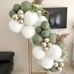 the balloon arch is decorated with white, green and gold balloons for an elegant touch