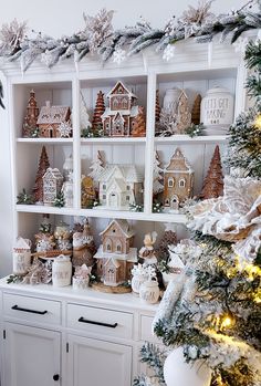 a white hutch filled with christmas decorations and gingerbread houses