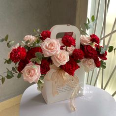 a white bag with red and pink flowers in it sitting on top of a table