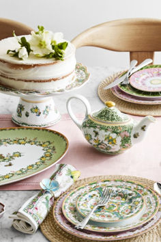 a table topped with plates and cups filled with cake next to a vase full of flowers