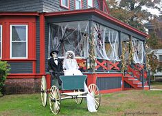 a bride and groom on a horse drawn carriage in front of a house with halloween decorations