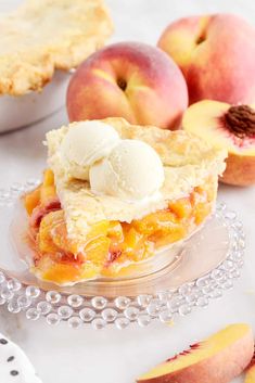 a slice of peach pie on a glass plate next to some sliced peaches and ice cream