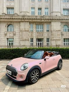 a pink mini convertible parked in front of a large building