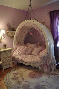 a canopy bed is in the corner of a room with purple curtains and pink walls