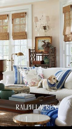 a living room filled with lots of furniture and pillows on top of a table in front of windows