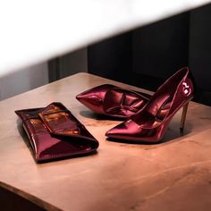 a pair of red high heel shoes sitting on top of a table next to a wallet