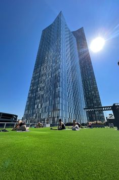 people laying on the grass in front of a tall building