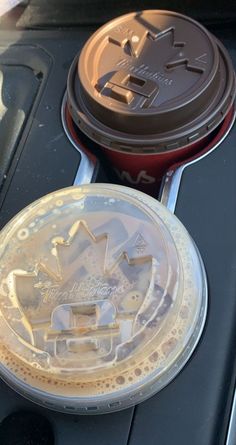 two plastic cups sitting on top of a car dashboard