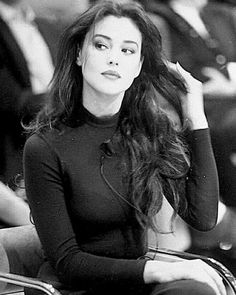 a black and white photo of a woman with long hair sitting in front of people