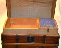 an old trunk is sitting on a table next to a white cloth covered tablecloth