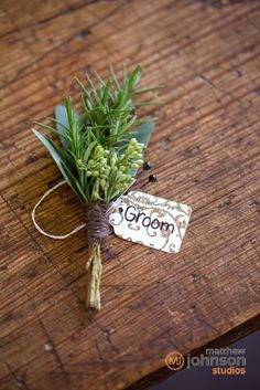 a bunch of green plants sitting on top of a wooden table next to a tag