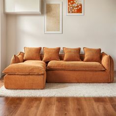 an orange couch sitting on top of a hard wood floor next to a white rug