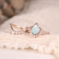 an opal and diamond ring on top of a white blanket