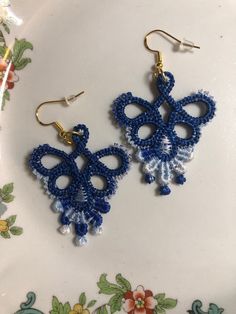 two pairs of blue and white beaded earrings on top of a floral design plate