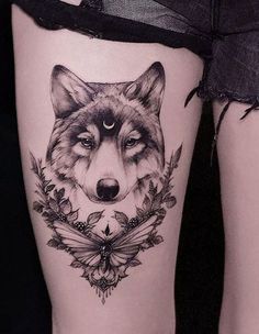 a woman's thigh with a wolf tattoo on it