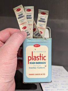 a hand holding a small blue lighter with four packets in it's holder and the words plastic read - bandages written on them