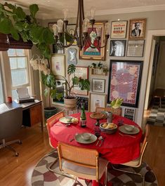 a dining room table is set with plates and place settings in front of pictures on the wall