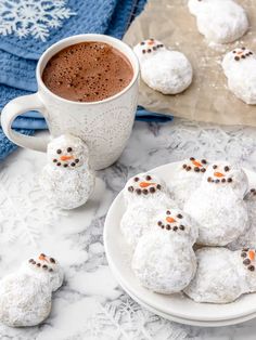 snowmen made out of powdered sugar on a plate next to a cup of hot chocolate