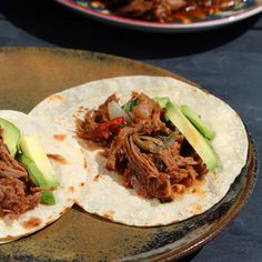 two tortillas with meat and avocado on them sitting on a plate