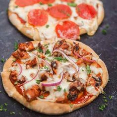 two pizzas sitting on top of a table covered in toppings