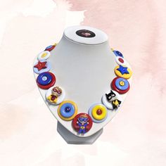 a necklace made out of buttons on a white mannequin with pink watercolor background