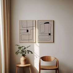 two paintings hang on the wall next to a chair and potted plant in a corner