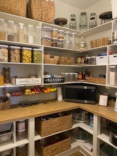 an organized pantry with lots of food in baskets and bins on the shelves next to the microwave