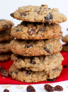 a stack of cookies with raisins on a red cloth next to some nuts