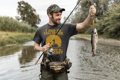 a man holding a fish while standing in the water