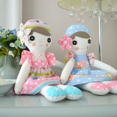 two stuffed dolls sitting on top of a table