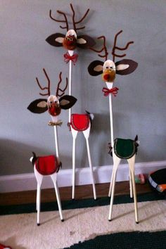 three reindeer made out of popsicle sticks on the floor in front of a wall