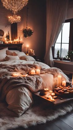 a bed with candles and blankets on it in front of a chandelier that is hanging from the ceiling