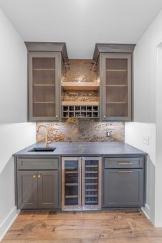 a kitchen with gray cabinets and wooden floors